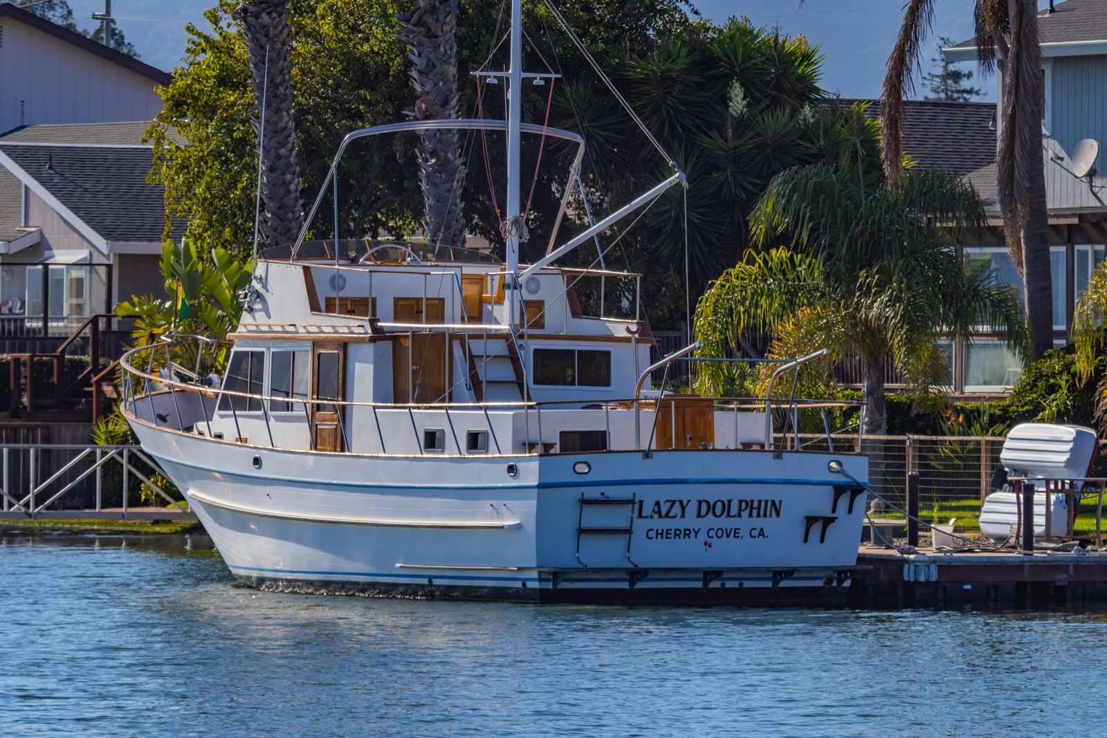 Boat transom lettered with the name Lazy Dolphin and hailing port Cherry Cove, CA