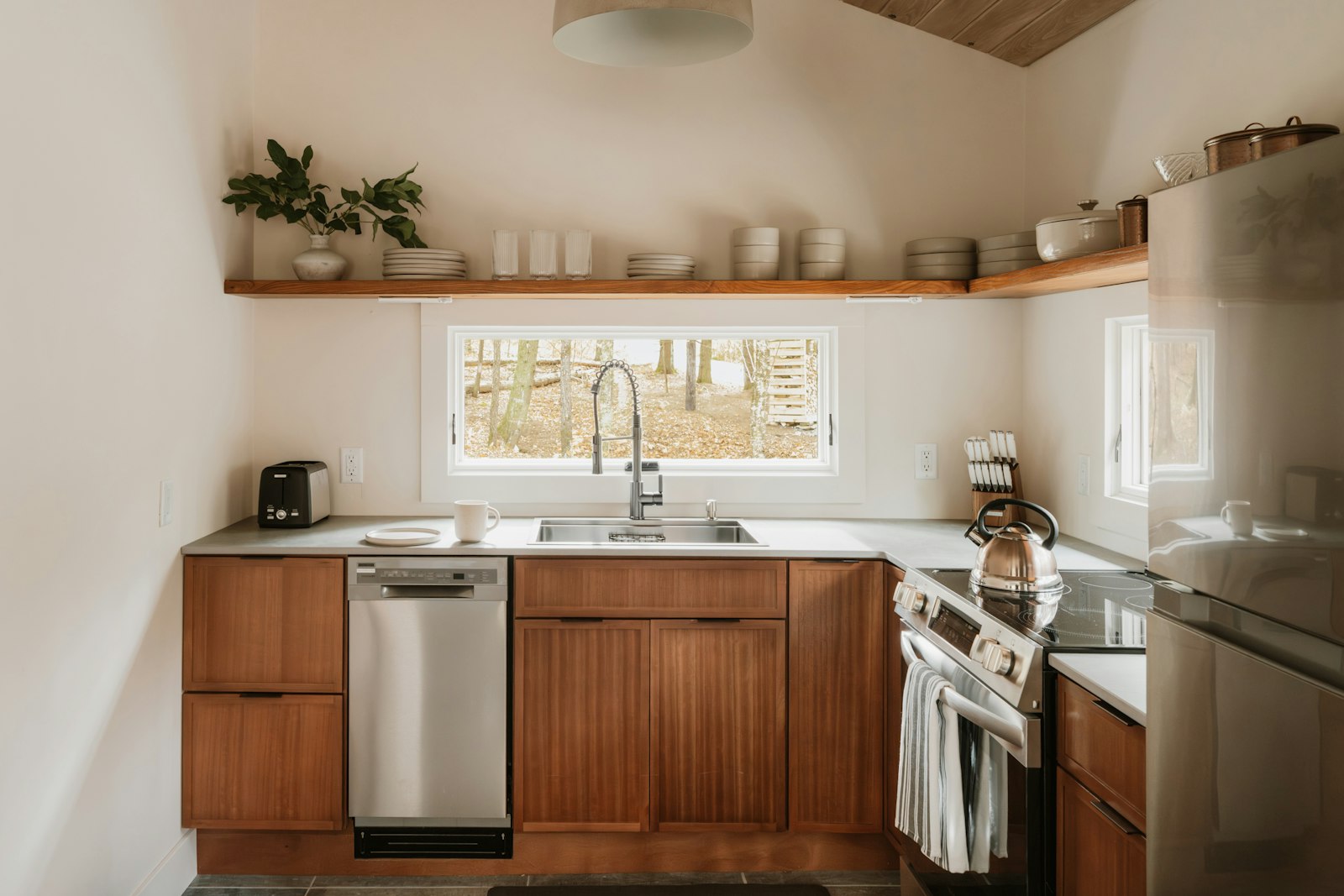 Modern kitchen with warm wood-grain cabinet fronts, stainless steel appliances and a light countertop