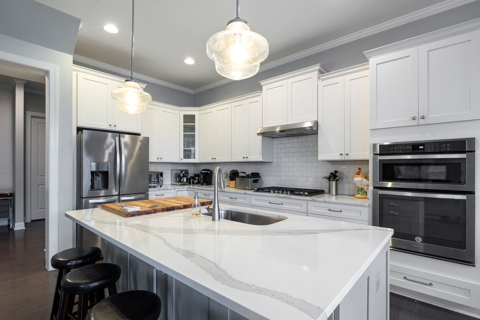 Kitchen island with white marble-look veined countertop and stainless faucet in a bright modern kitchen