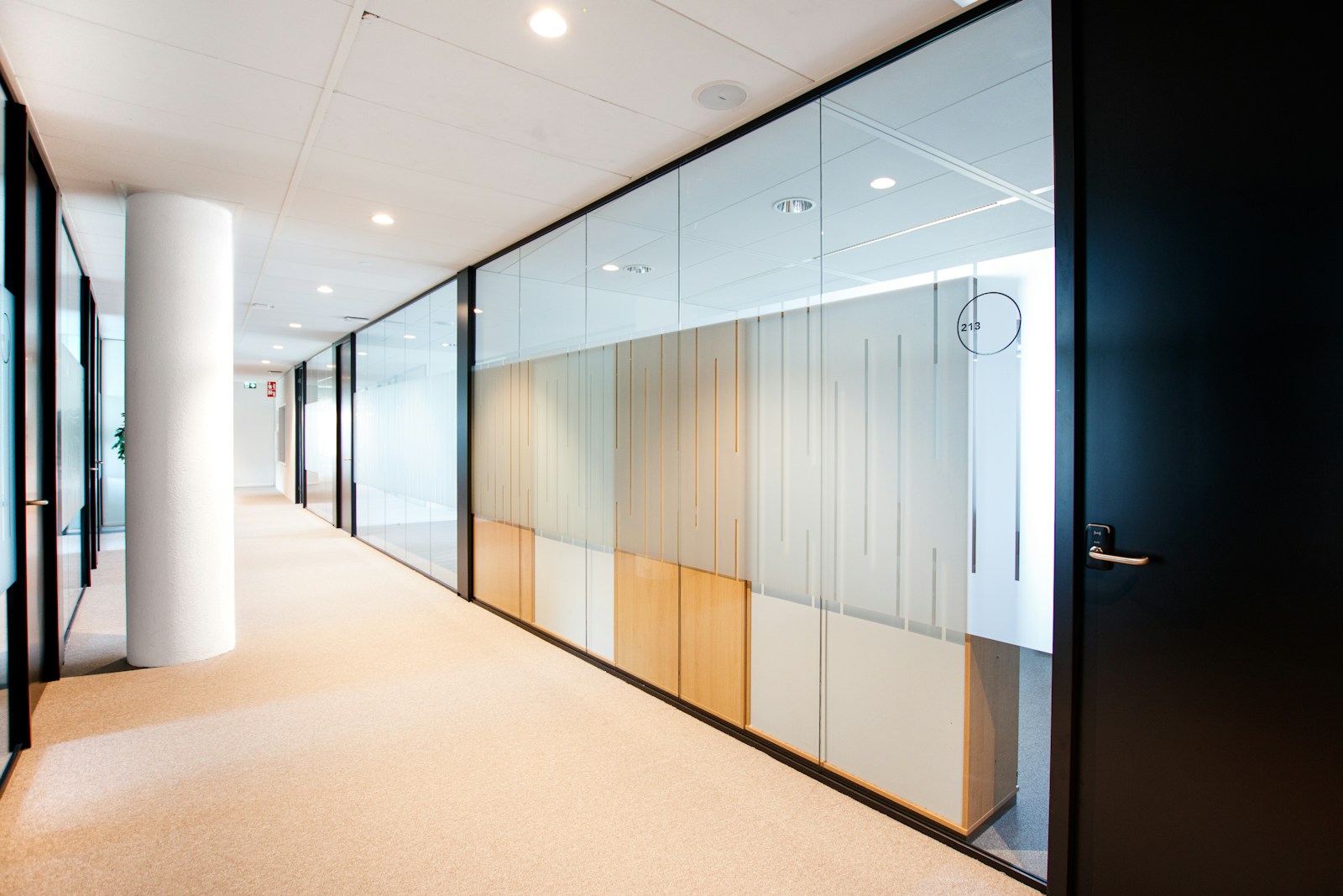 Bright office corridor with decorative frosted-film gradient bands applied to glass partition walls