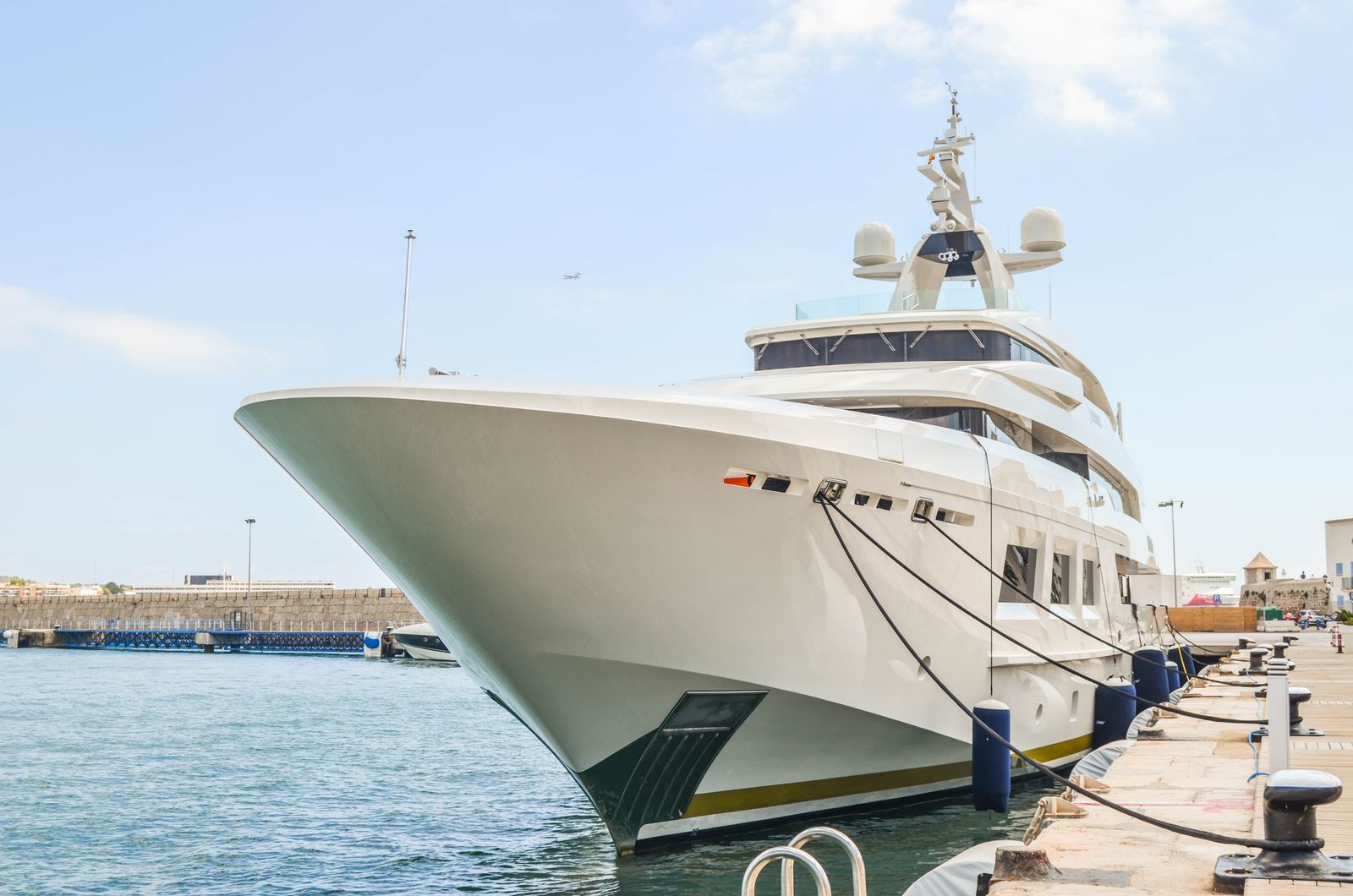 Gleaming white motor yacht hull moored at a marina dock on a sunny day