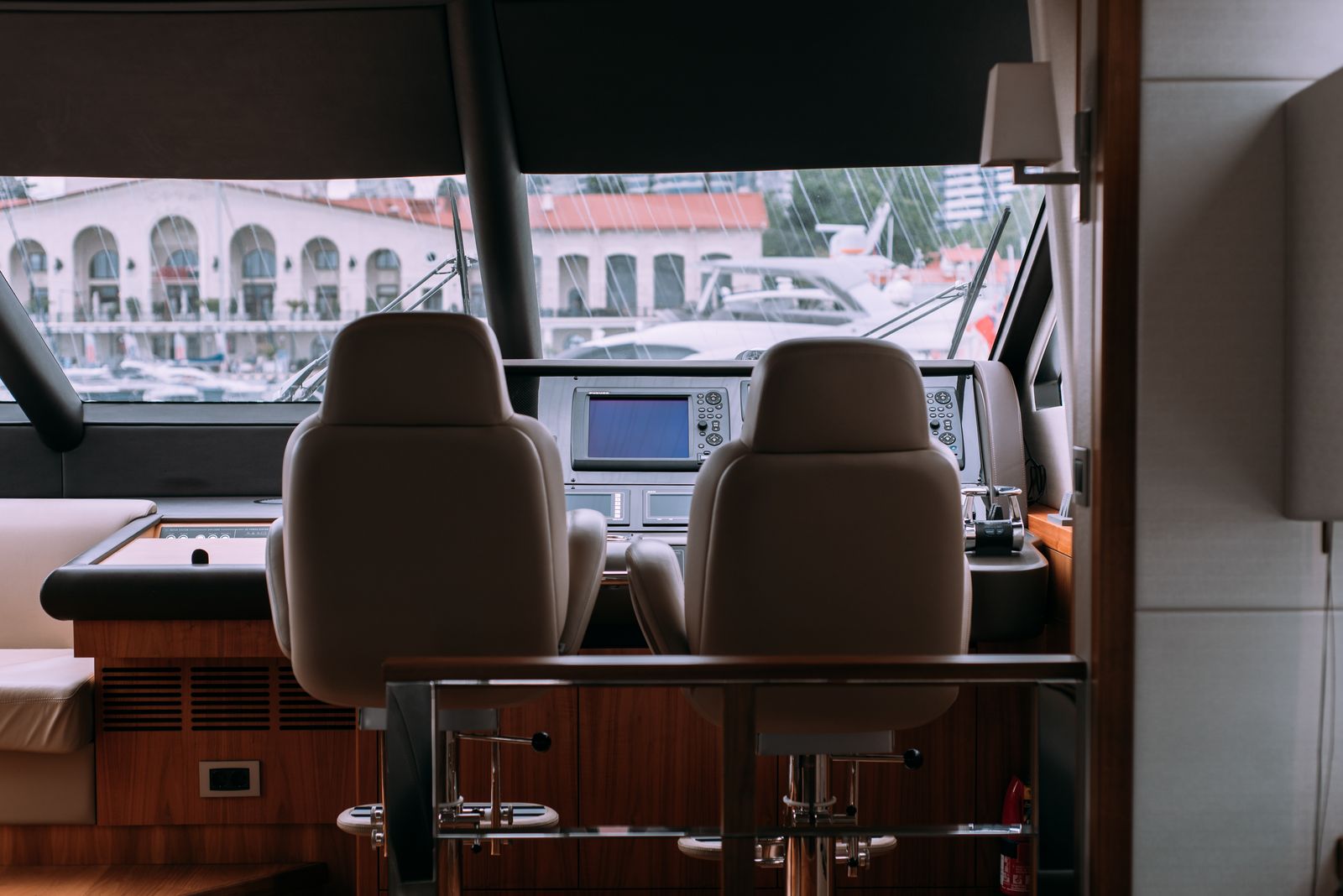 Yacht helm station interior with leather helm chairs and wood-veneer cabinetry