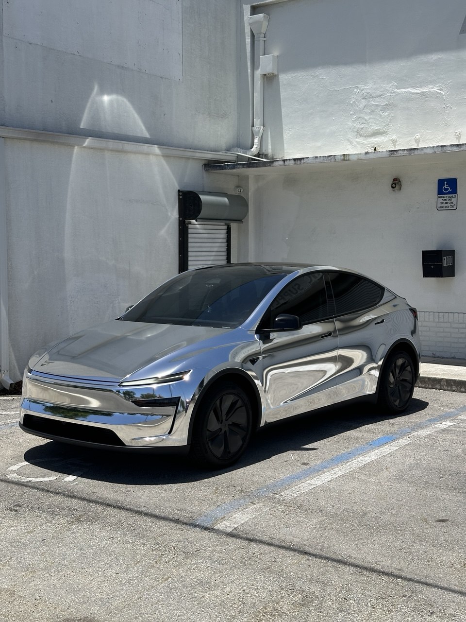 Tesla Model Y in mirror chrome with blacked-out trim parked outside the Wrap Trap shop in Hollywood, FL